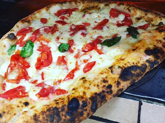 pizza Anita, ripieno di ciccioli, friarielli e provola, centro con pomodorini, mozzarella fiordilatte, scagli e di grana, basilico e olio e.v.o.